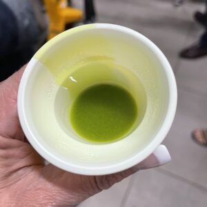 Close-up of freshly pressed bright green extra-virgin olive oil in a tasting cup during olive oil mill visit in Sicily.