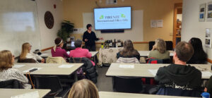 Donna Liotto-Scocozza stands before a classroom of attendees, as she begins an olive oil and lifestyle workshop and showing EVOO samples.